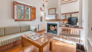 A living room with a sofa, a wooden coffee table, a fireplace, and a television.