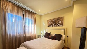 Un dormitorio con una cama grande, una mesita de noche, una lámpara y un cuadro en la pared.