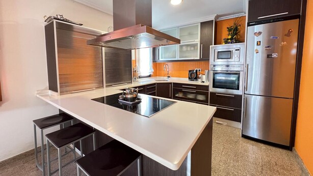 Una cocina moderna con una isla central, electrodomésticos de acero inoxidable y armarios de madera oscura.