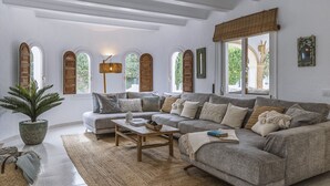 A spacious living room with a large grey sectional sofa, a wooden coffee table, and a potted plant. - Villa Artista (Javea / Xàbia)