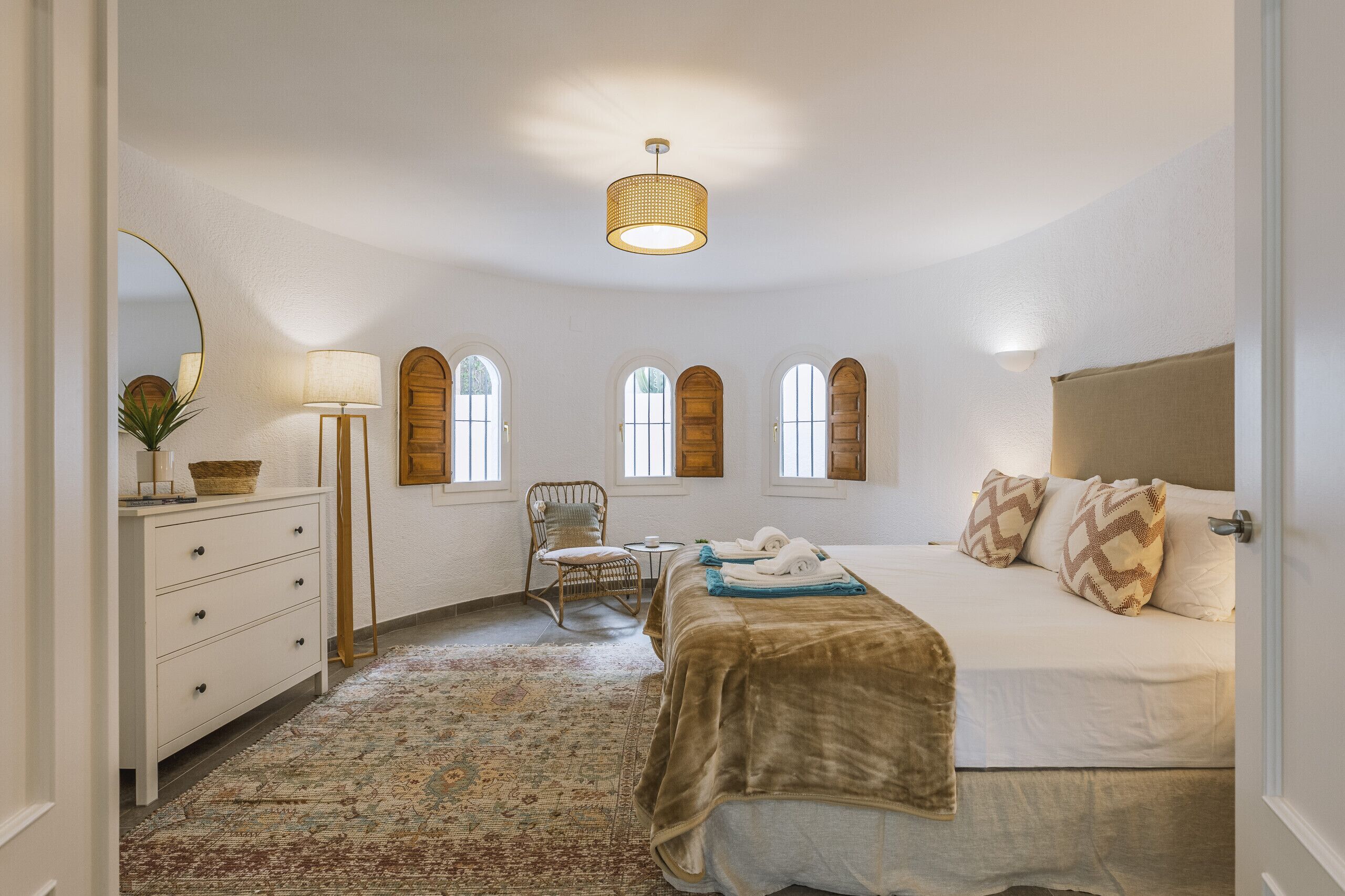 A bedroom with a bed, a dresser, a chair, a lamp, and a window.