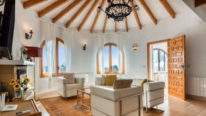 Un salon spacieux avec un haut plafond, de grandes fenêtres et une cheminée.
