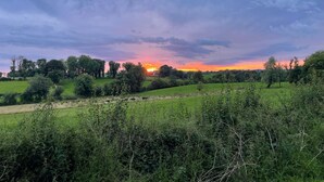 A rural landscape with rolling hills, a sunset, and scattered trees. - Littlemount Farm Cottage (Enniskillen)