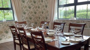 A dining room with a wooden table set for six, surrounded by six chairs. - Littlemount Farm Cottage (Enniskillen)