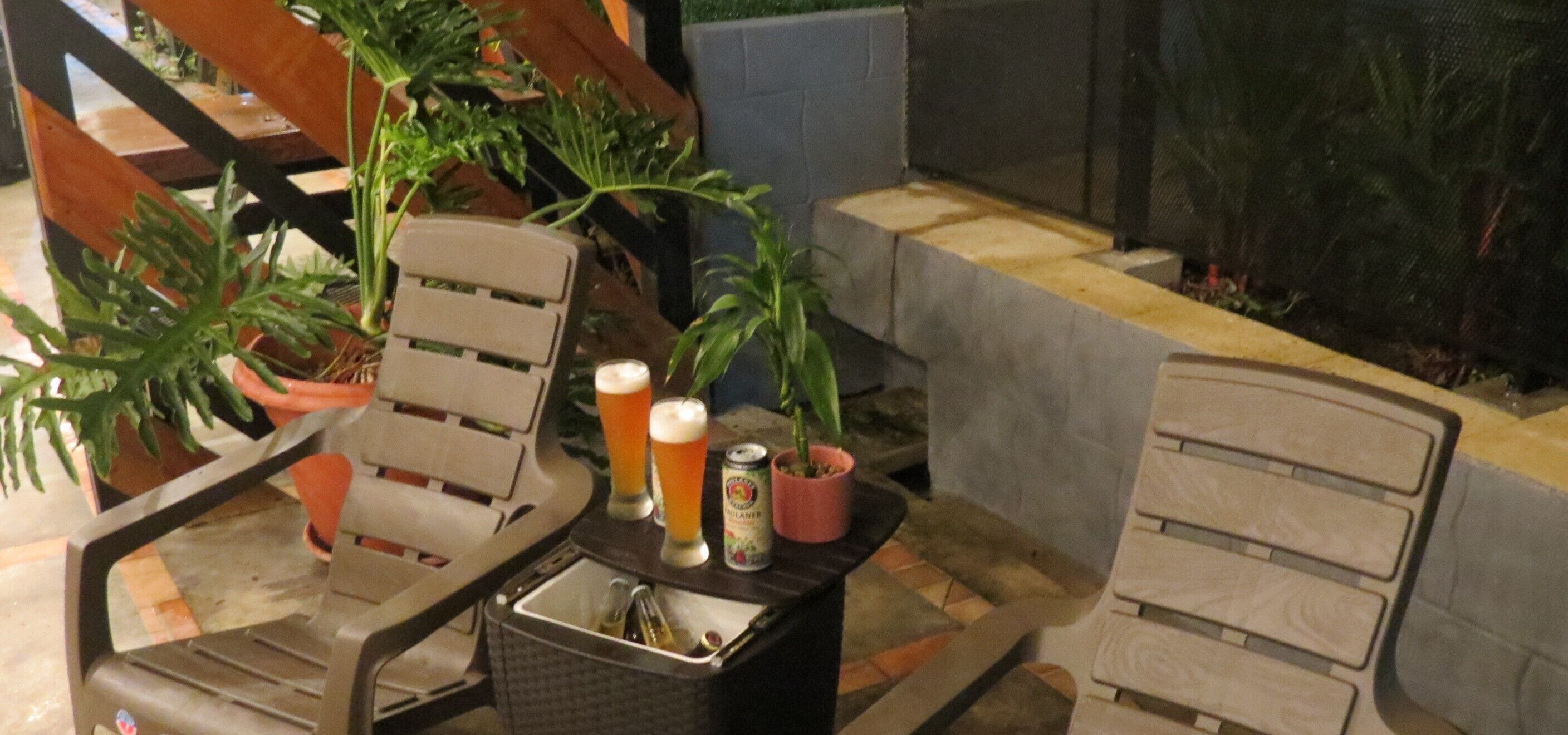 En terrasse med udendørs møbler, et bord med drikkevarer og krukkeplanter.