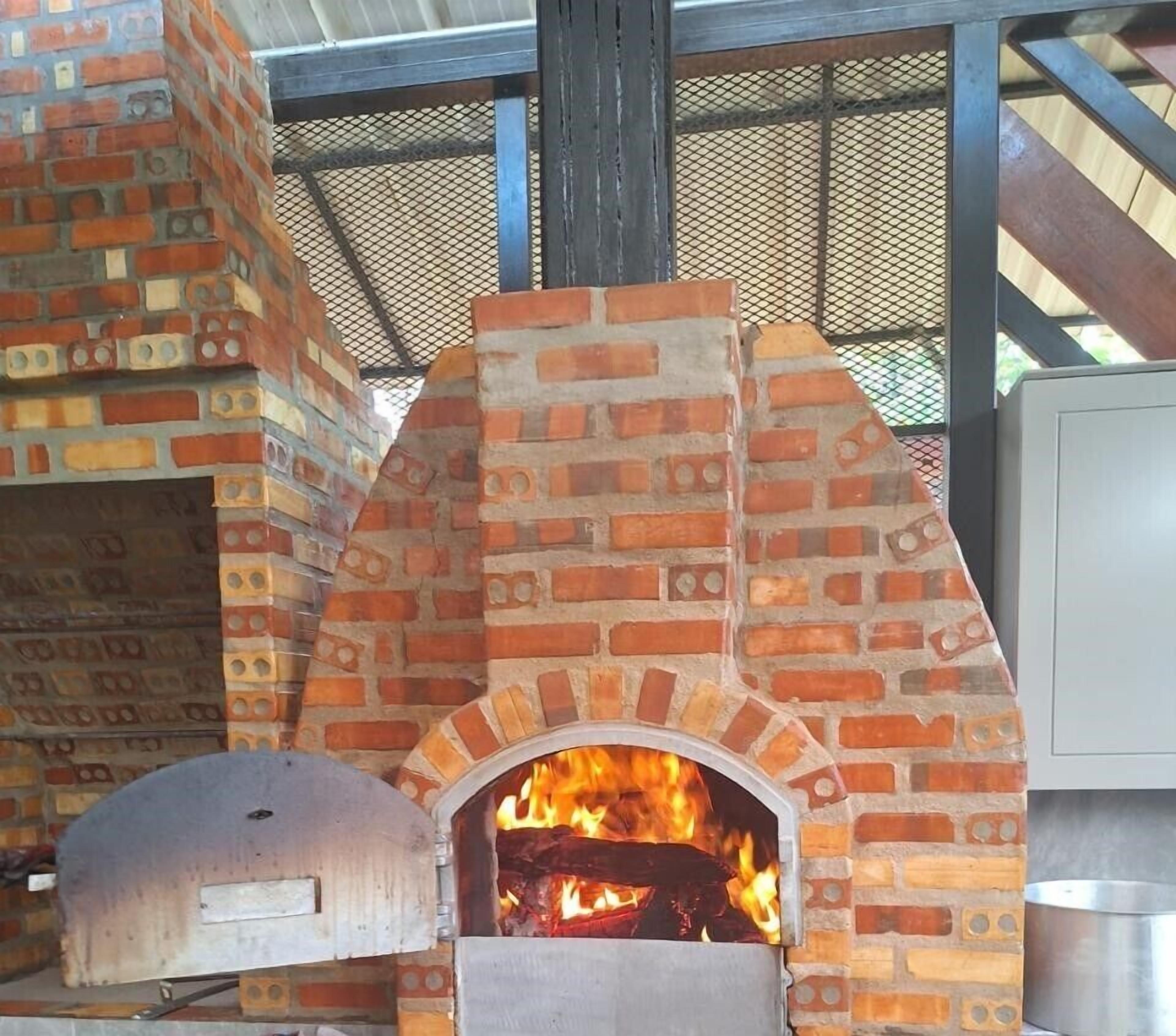 A brick oven pizza oven with a fire burning inside.