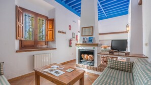 A living room with a fireplace, a television, a sofa, and a table with books and magazines. - Apartment 'Apartamento La Cuadra' with Mountain Views, Shared Pool, and Wi-Fi (La Zubia)