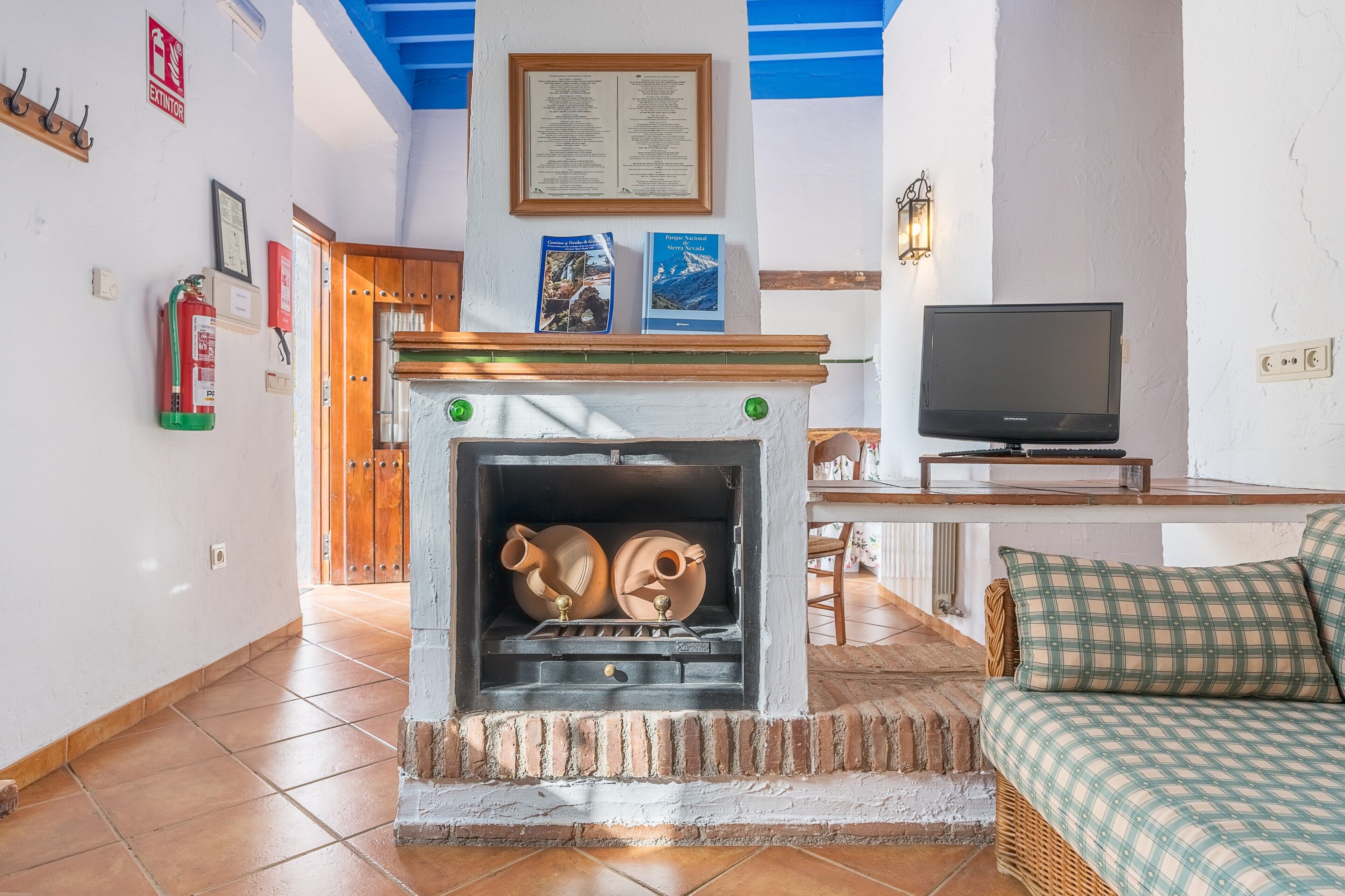 Una sala de estar con chimenea, televisor y sofá de mimbre.