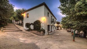 A building with a white exterior, a tiled roof, and a paved driveway. - Apartment 'Apartamento La Cuadra' with Mountain Views, Shared Pool, and Wi-Fi (La Zubia)