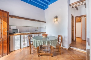 Una cocina con una mesa redonda, sillas, microondas y un lavamanos.