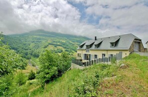 A house with a stone foundation, a sloped roof, and a balcony.