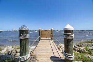 A wooden pier leading to a dock with a wooden gate, surrounded by calm water and a clear sky. - Minutes to Beach Pool Intracoastal Free Kayaks/Bikes, Intracoastal Sea Life Retreat (Holly Hill)