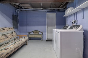 A laundry room with a washing machine, a bench, and a door.