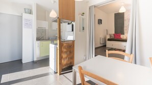 A modern kitchen with white cabinets, a wooden partition, and a dining area with a white table and chairs. - Chalet "De Sers" with Mountain Views, Private Terrace and Wi-Fi (Sers)