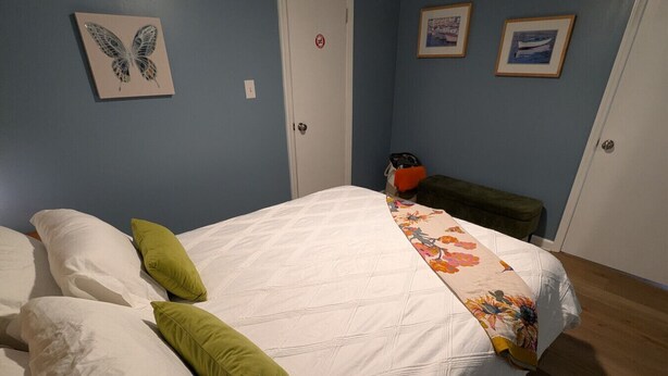 Une chambre à coucher avec un lit, des oreillers, une couverture, une porte et deux tableaux encadrés accrochés au mur.