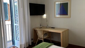 A room with a bed, a desk with a chair, a television, and a framed picture on the wall. - Spanish Steps Luxury Double Room (Roma)