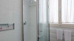 A bathroom with a glass shower enclosure, a towel rack, and a window with curtains. - Spanish Steps Luxury Double Room (Roma)
