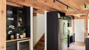 Une cuisine moderne avec des poutres en bois, un réfrigérateur encastré et un escalier en bois.