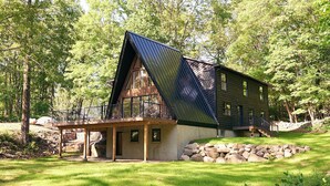 Une maison moderne avec un toit en pente, de grandes fenêtres et des fondations en pierre.