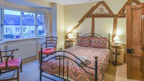 A bedroom with a bed, two chairs, a window, and a wooden ceiling structure. - 3 bedroom accommodation in Ludlow (Ludlow)