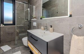 Une salle de bain moderne avec une grande baignoire, une douche à l’italienne et des toilettes.