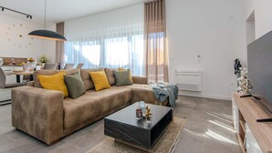A modern living room with a sectional sofa, a coffee table, and a dining area with a table and chairs. - StunNing home in Nin with sauna (Nin)