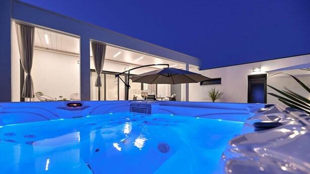 An indoor swimming pool with a jacuzzi, large windows, and a dining area with outdoor seating. - StunNing home in Nin with sauna (Nin)