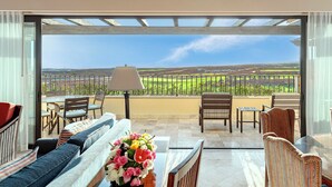 Un balcon donnant sur un paysage verdoyant, aménagé avec un canapé, des fauteuils et une table.
