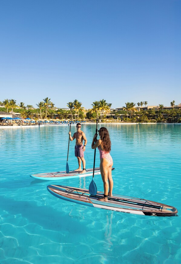 Two people paddleboarding in a clear blue pool with a resort background. - The Reserve at Diamante Cabo San Lucas (Cabo San Lucas)