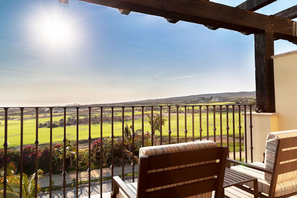 Varanda com vista para um campo de golfe e colinas ao longe.