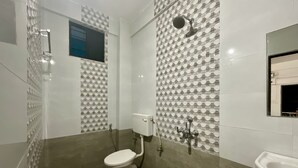 Une salle de bain comprenant des toilettes, une douche avec un pommeau de douche amovible et un lavabo.
