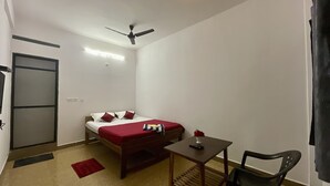 Une petite pièce bien éclairée, avec un lit, une table et une chaise.