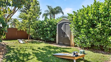 A backyard with a shed, a wooden table, and a trampoline.