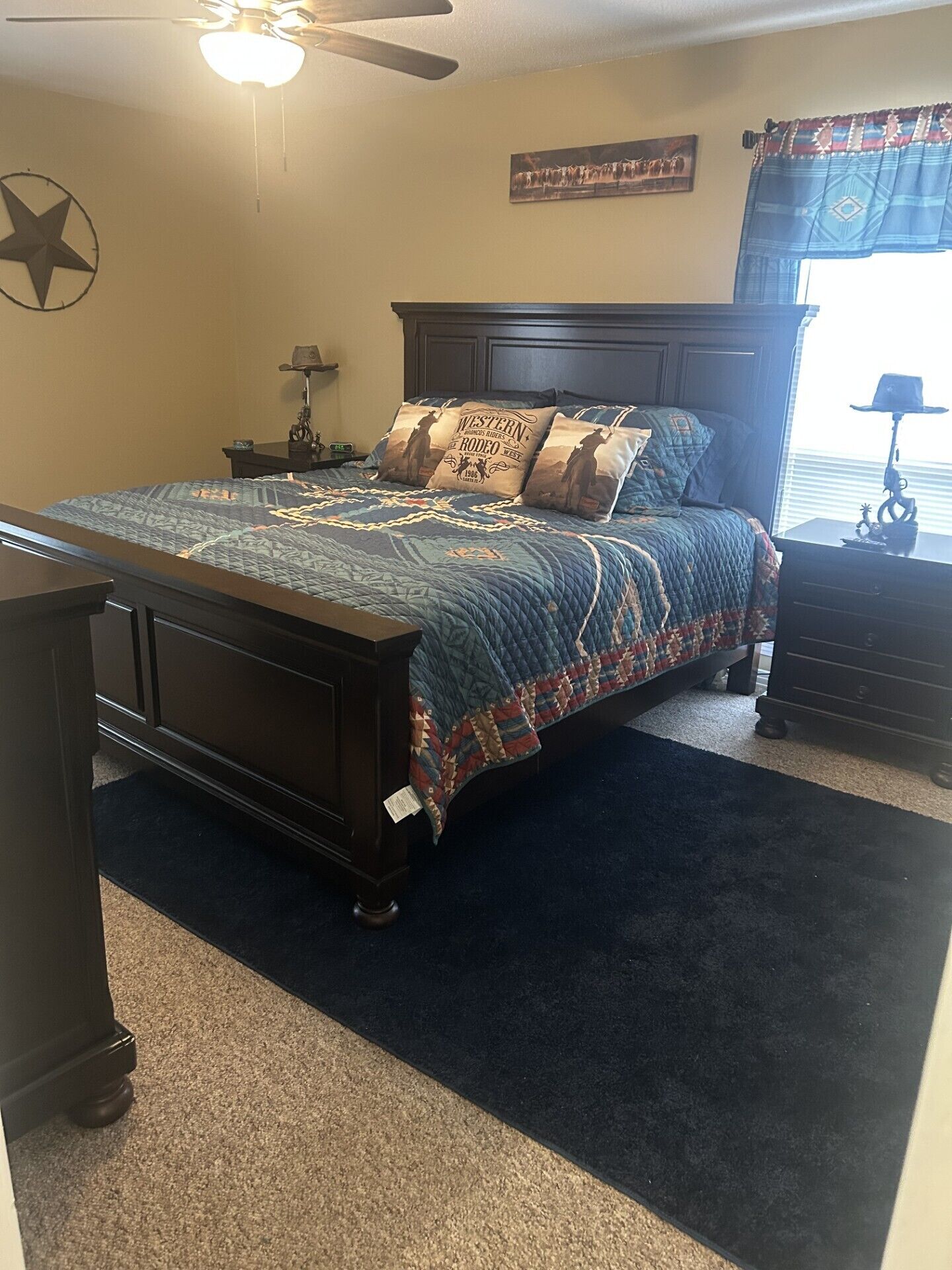 A bedroom with a dark wooden bed, a star decoration on the wall, and a window with a curtain.
