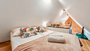 A cozy bedroom with a bed, pillows, and a view of a brick wall.