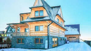 A wooden house with a steeply pitched roof, a balcony, and a garage.