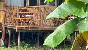 Une maison en bois dotée d’un balcon et de grandes fenêtres, entourée de verdure.