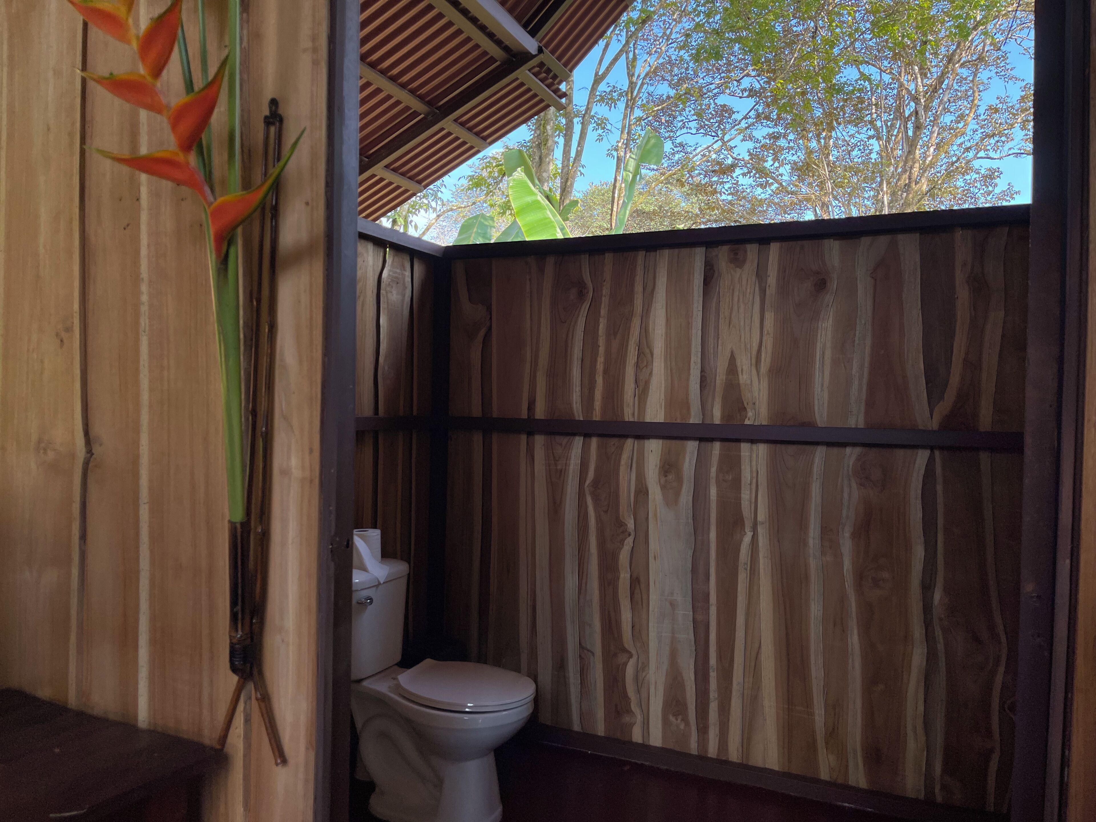 Une salle de bain en bois avec des toilettes et un espace douche.