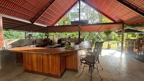Une cuisine spacieuse dotée d’un grand îlot central en bois, d’appareils électroménagers en acier inoxydable et offrant une vue sur un paysage verdoyant.