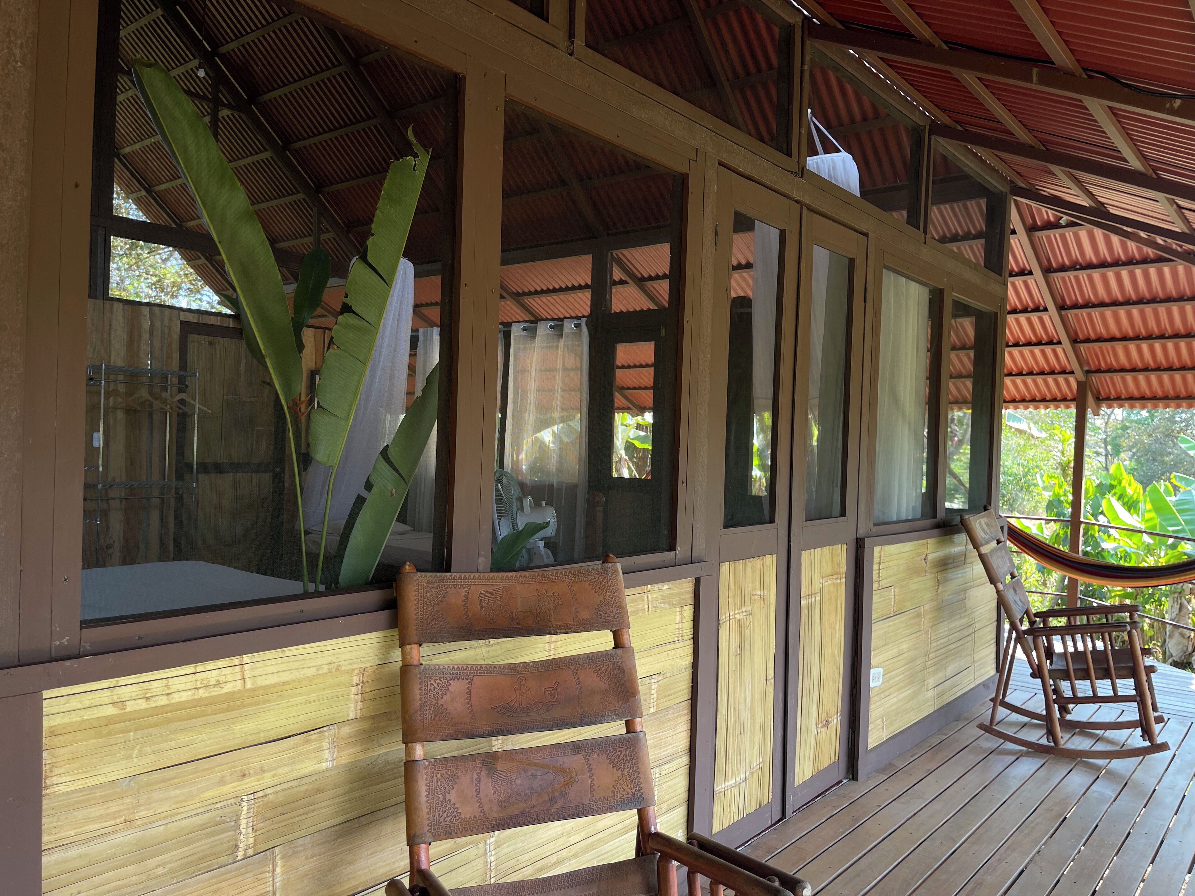 Una terraza de madera con una mecedora y una hamaca.