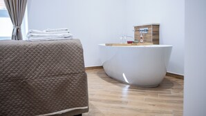 A modern bathroom with a freestanding bathtub, a wooden vanity, and a neatly folded towel stack. - Dimora Diaz B&B (Naples)