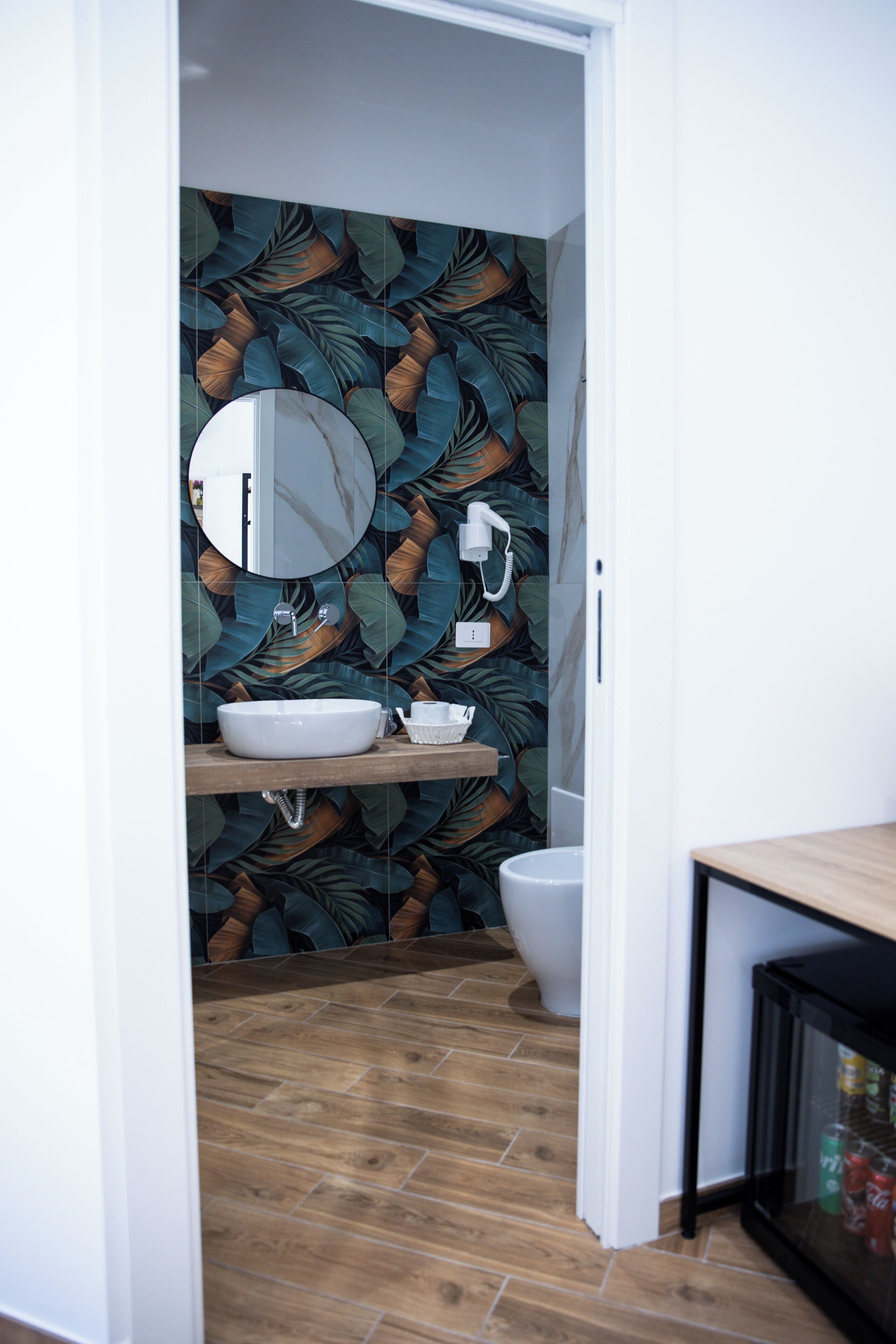 A bathroom with a wooden floor, a white sink, a mirror, and a toilet.