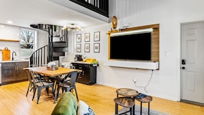 A modern kitchen with a dining area, a staircase, and a mounted TV. - Sleeps 12, HOT TUB, Cowboy Pool, Firepits, Yard Games (Louisville)