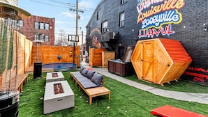 A backyard with a basketball hoop, a wooden bench, a small pool, and a neon sign on the wall. - Sleeps 12, HOT TUB, Cowboy Pool, Firepits, Yard Games (Louisville)