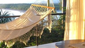 A hammock on a balcony overlooking a river and greenery. - Mar & Sombra Villas (Quepos)