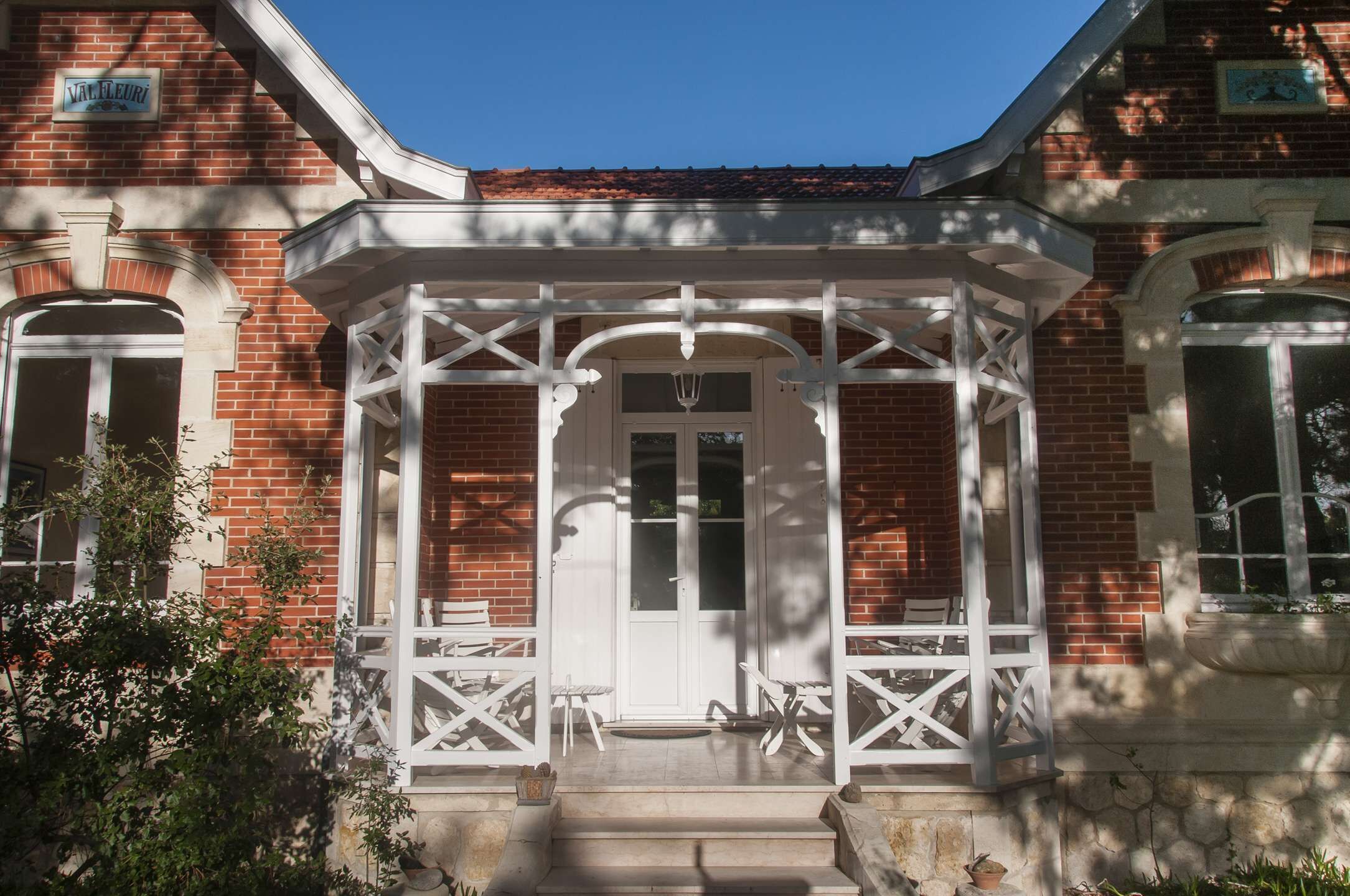 Ein Backsteinhaus mit weißem Veranda und einer Tür.