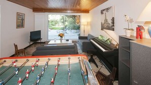 Un salon chaleureux avec un baby-foot, un piano et un téléviseur.