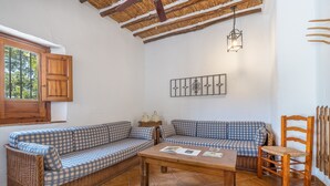 Una habitación acogedora con un sofá a cuadros, una mesa de madera y una silla de mimbre.