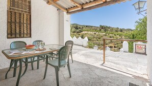 Una mesa con sillas, una ventana con barrotes y vistas a un paisaje montañoso.