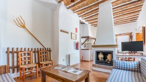 Una sala de estar acogedora con una mesa de madera, dos sillas, un sofá y un televisor.